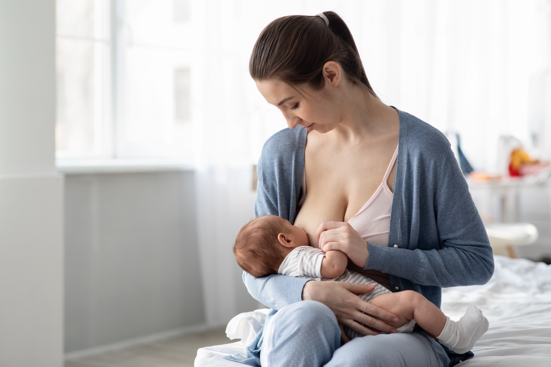 Portrait Of Young Beautiful Woman Breastfeeding Her Infant Child At Home