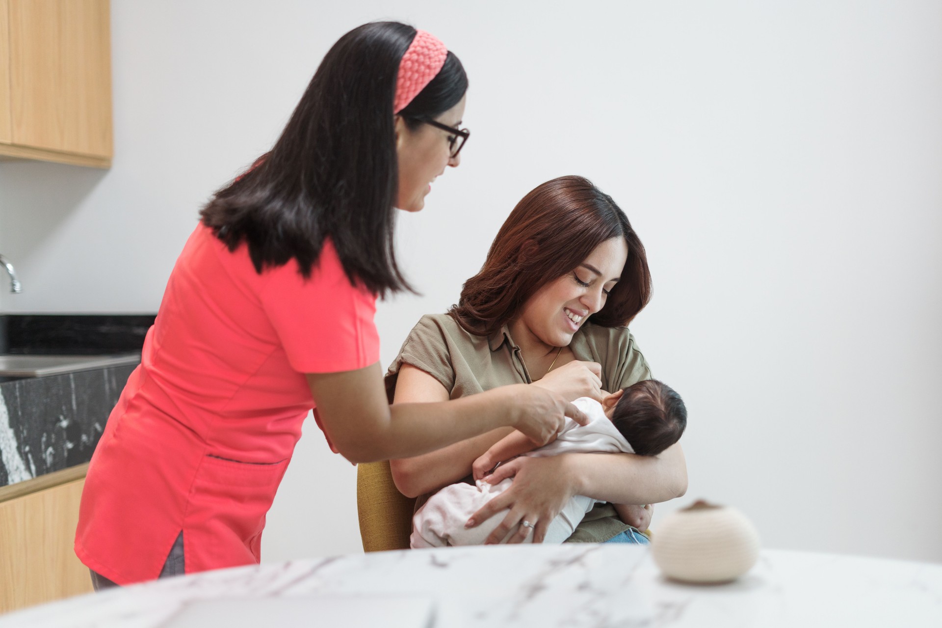 Mother breastfeeding with nurse's help