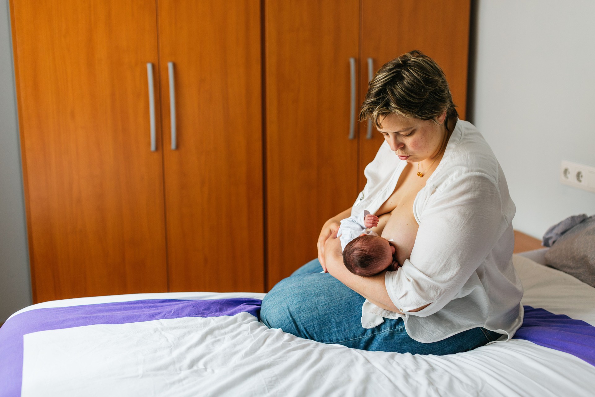 Mother breastfeeding her one month old baby on bed